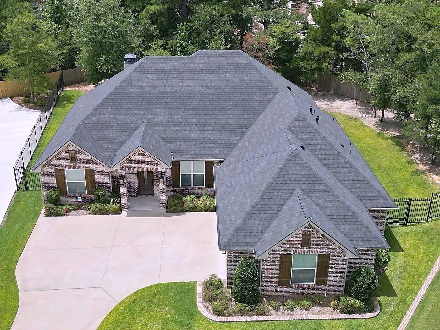 Front of a single-story brick home with a gray shingle hip roof