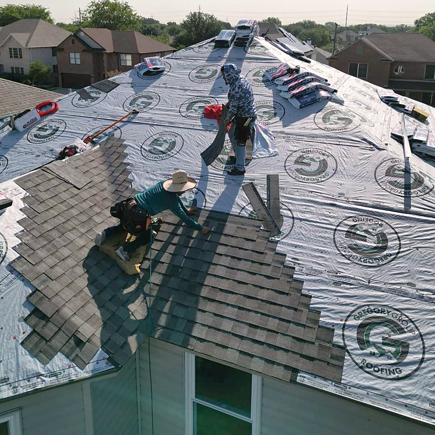 A roofer standing on synthetic underlayment during a tear-off