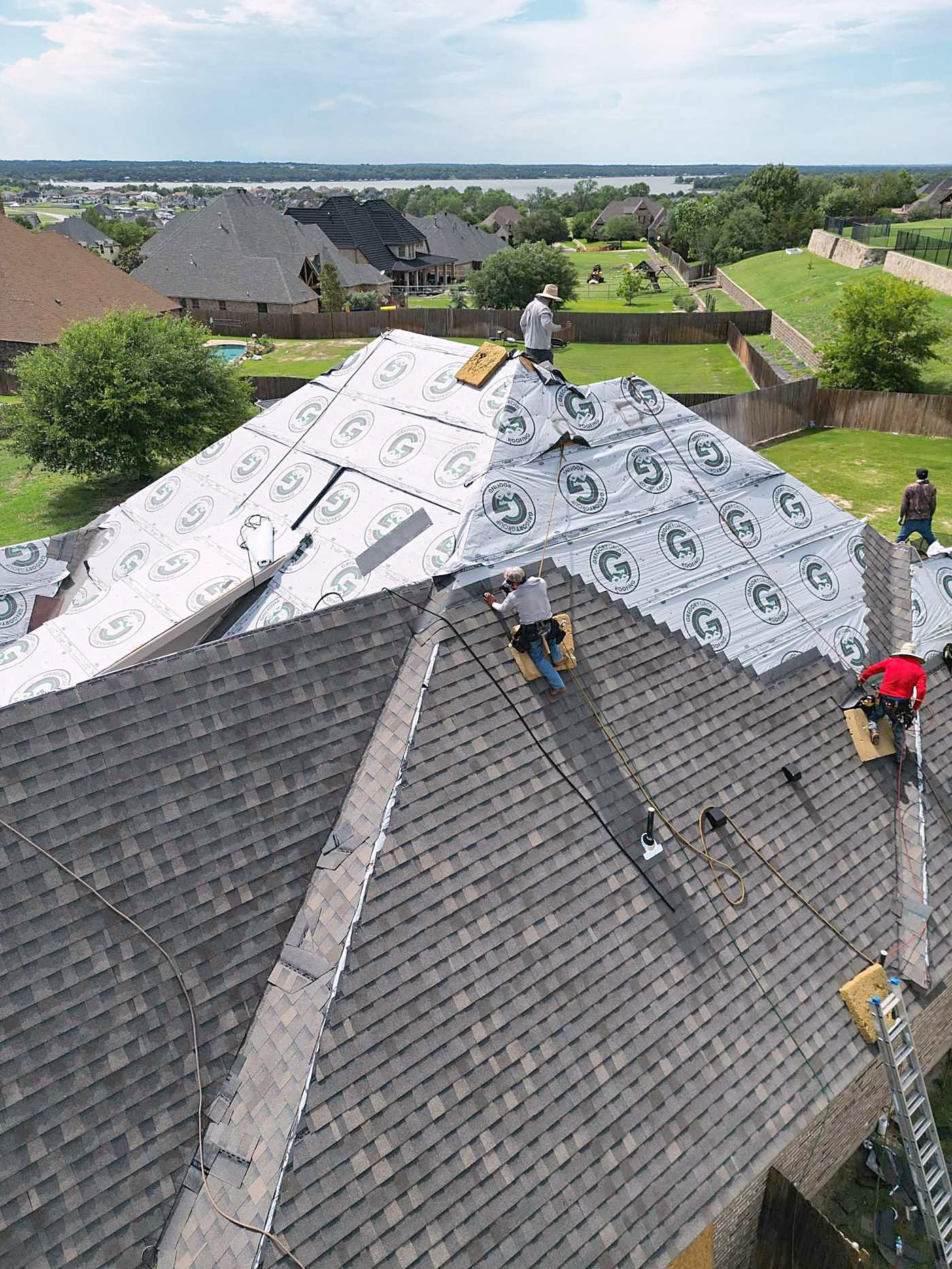 Roofers laying shingles over new underlayment on a steep roof