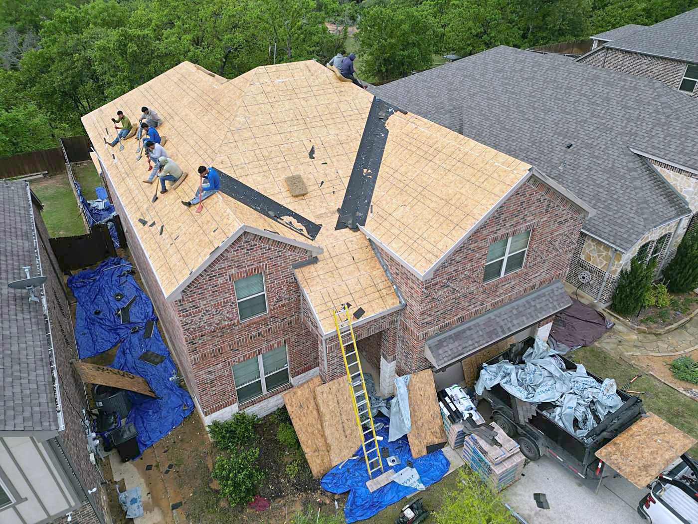 A brick home with the old roof removed and bare decking exposed