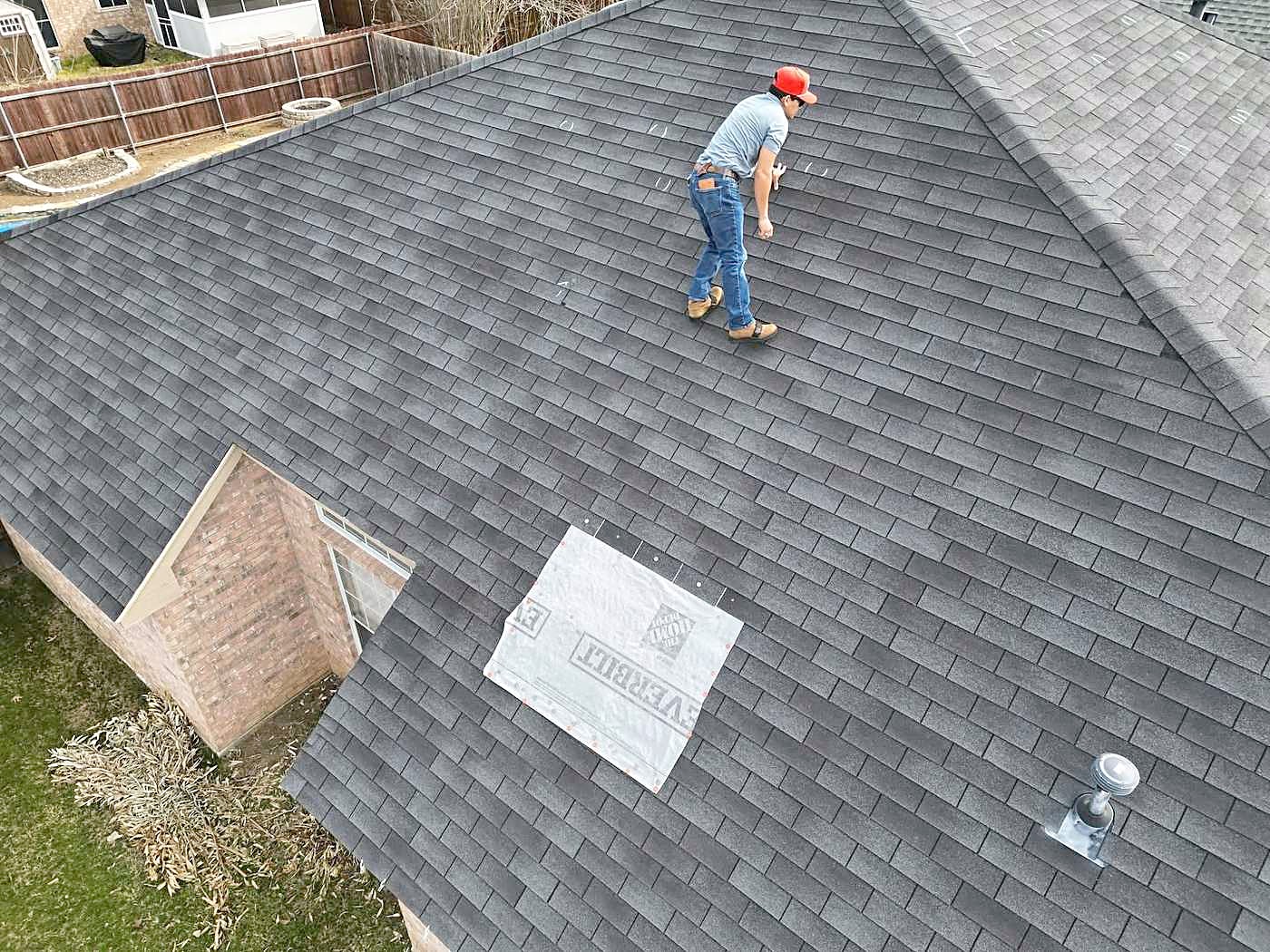 A roofer walking a shingle roof during an inspection