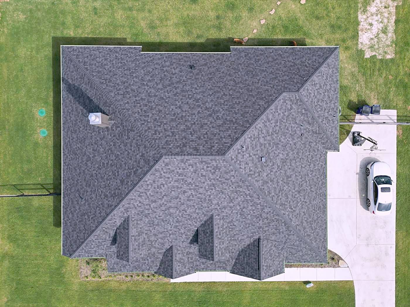 Top-down view of a finished hip roof in dark gray shingles