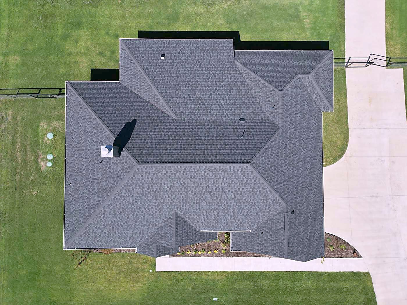 Overhead view of a newly shingled roof beside a concrete drive